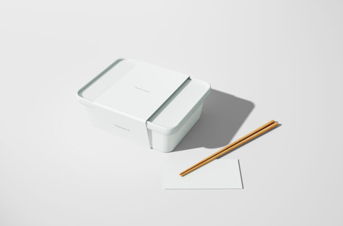 Embalagem minimalista branca com hashis de madeira e papel de apoio sobre fundo neutro.